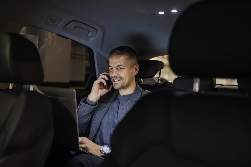Zakenman die al werkend in een taxi zit
